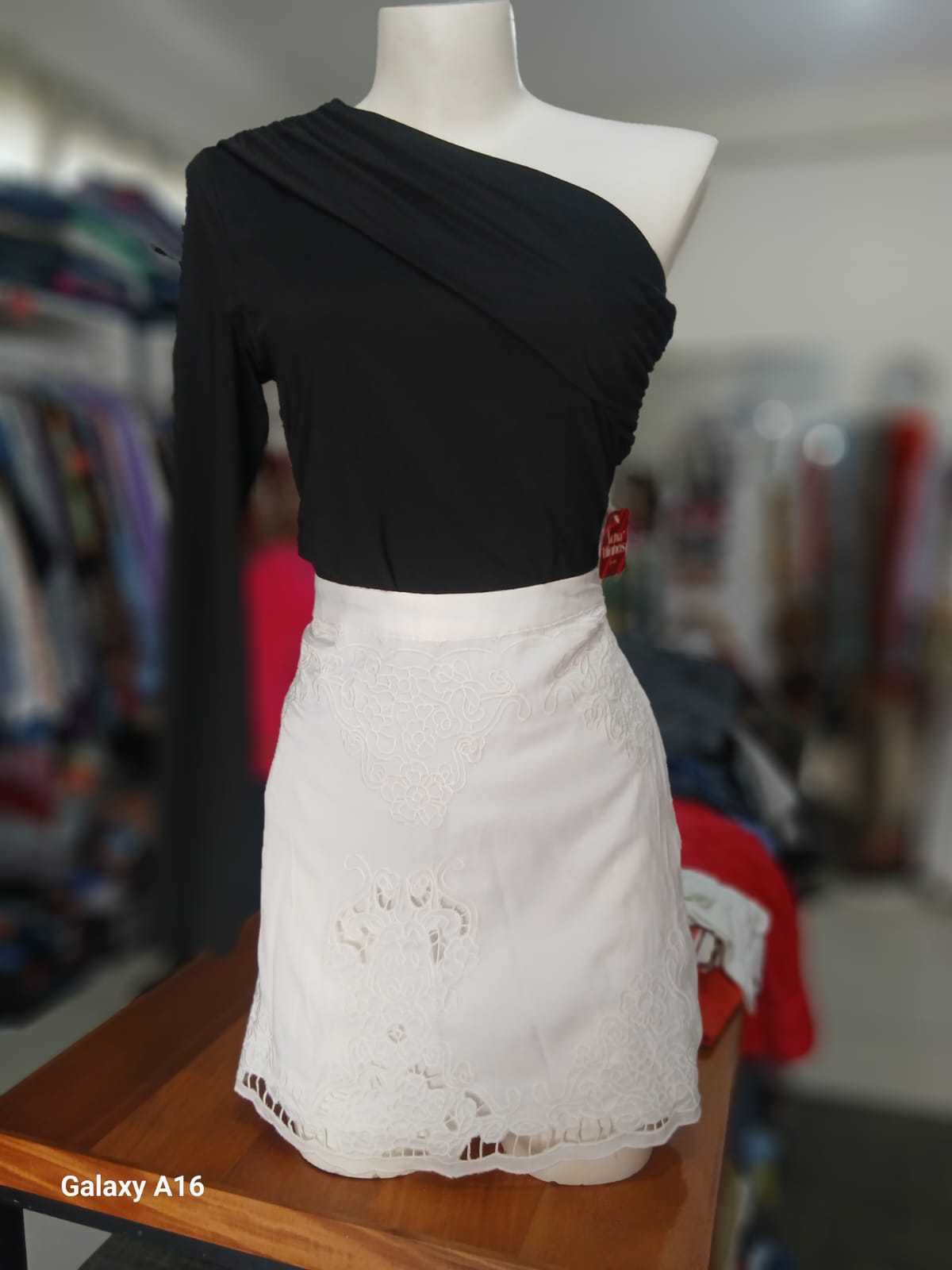Blusa preta de um ombro com saia branca de renda